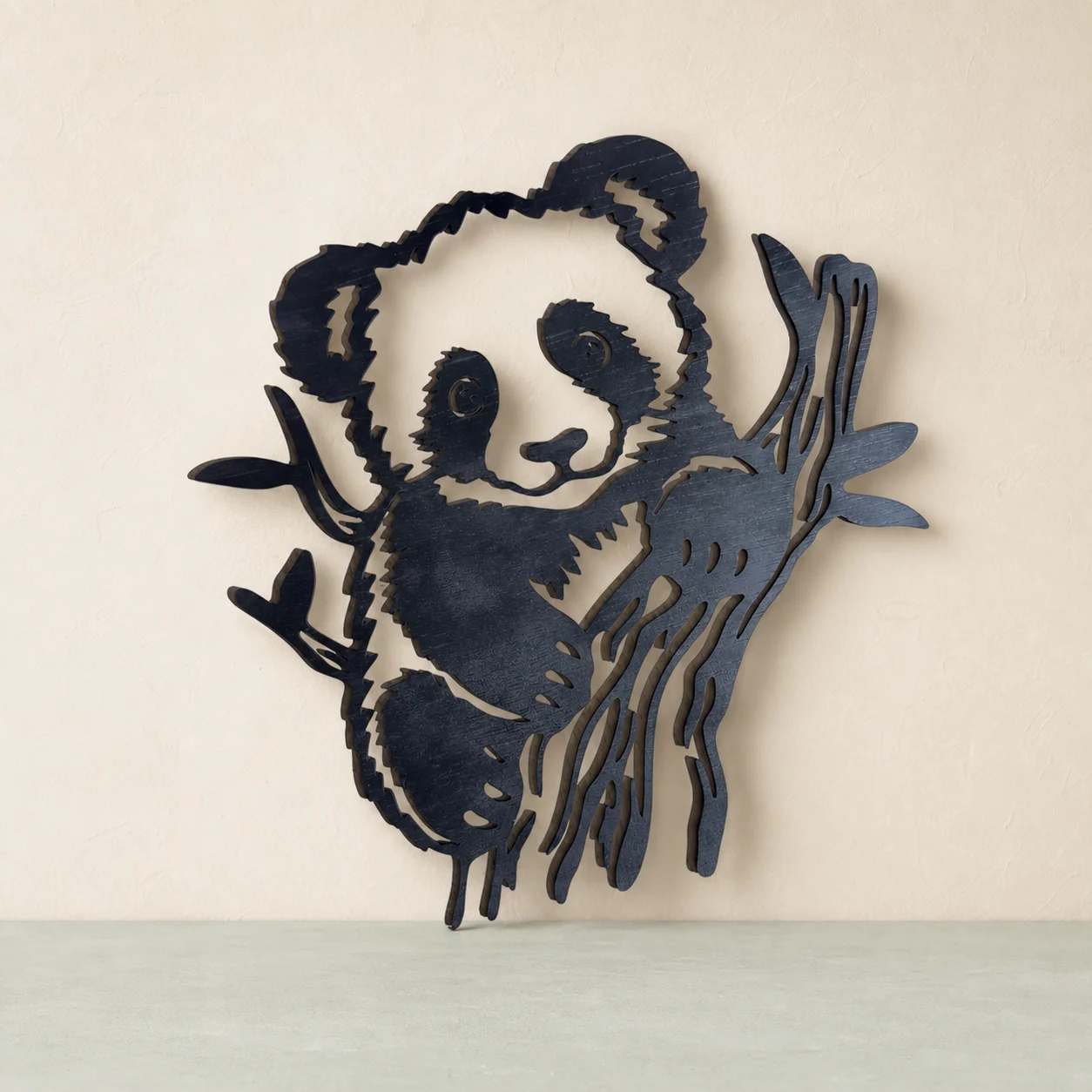 Decor negru din lemn cu un panda alb-negru care se ține de o creangă